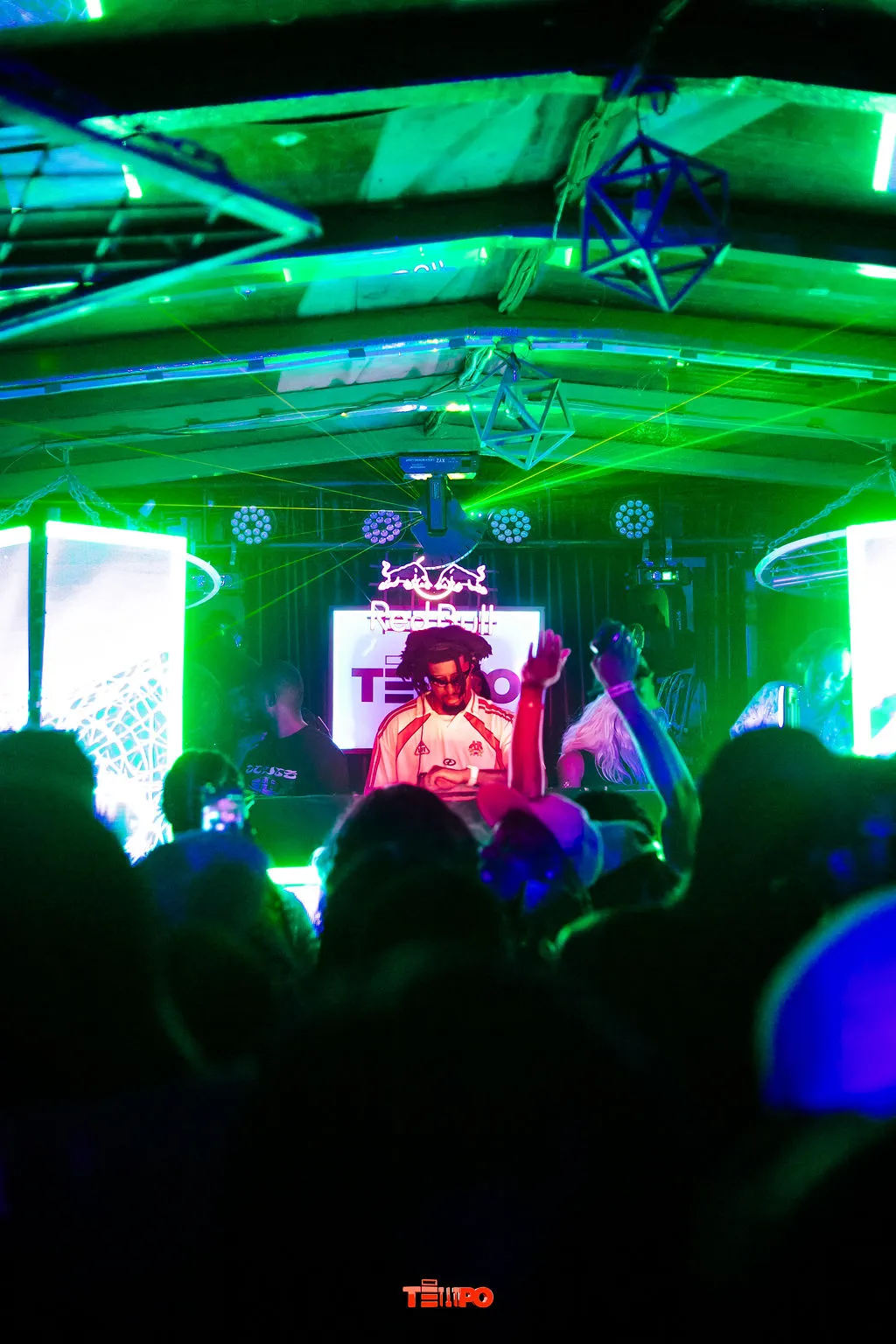 The crowd facing the DJ booth under green lasers at KLUB TEMPO
