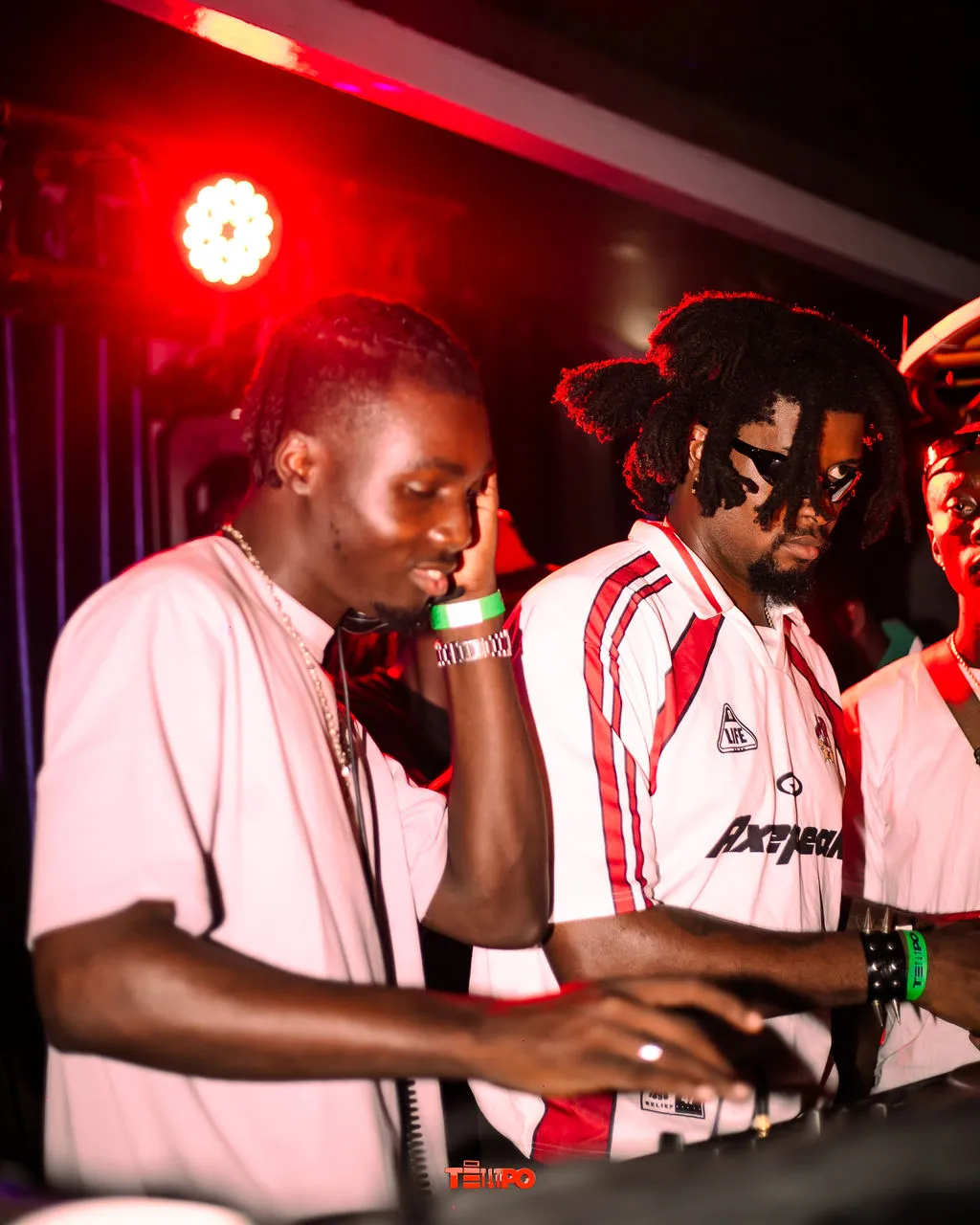 Two DJs working the decks under red light