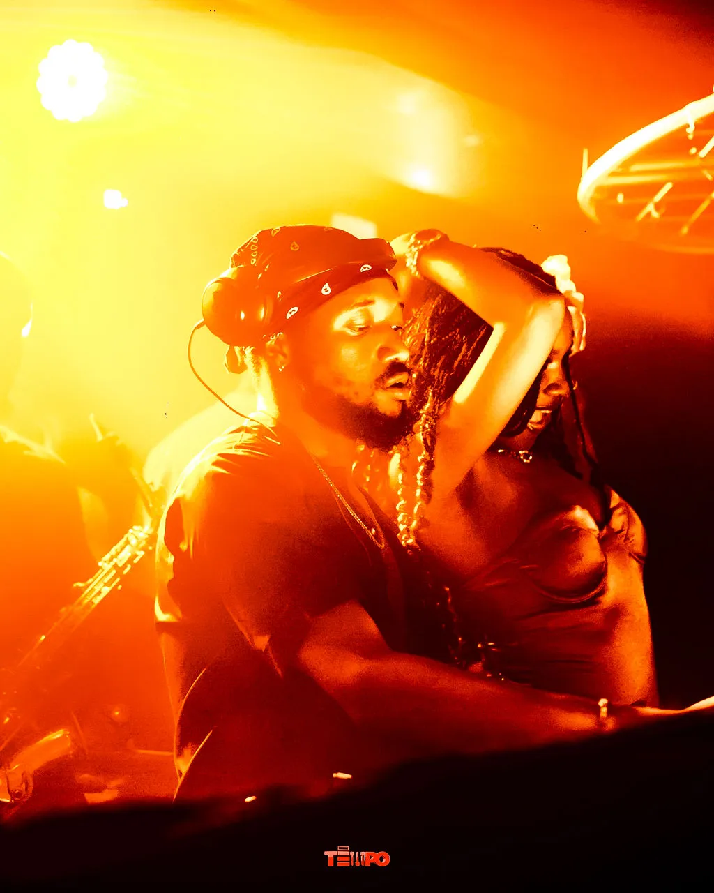 A DJ throwing his hands up in amber light
